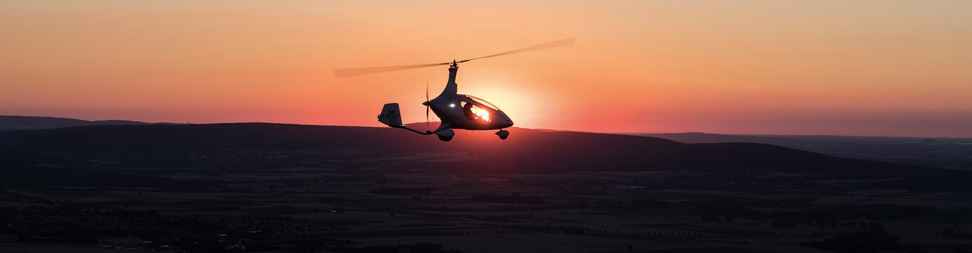 Gyroplane silhouette against an orange sunset over the Lowveld
