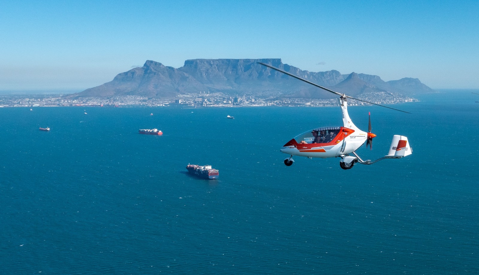 Ship at 600 ft over Franschhoek bowl — village white-washed below, mountains beyond.
