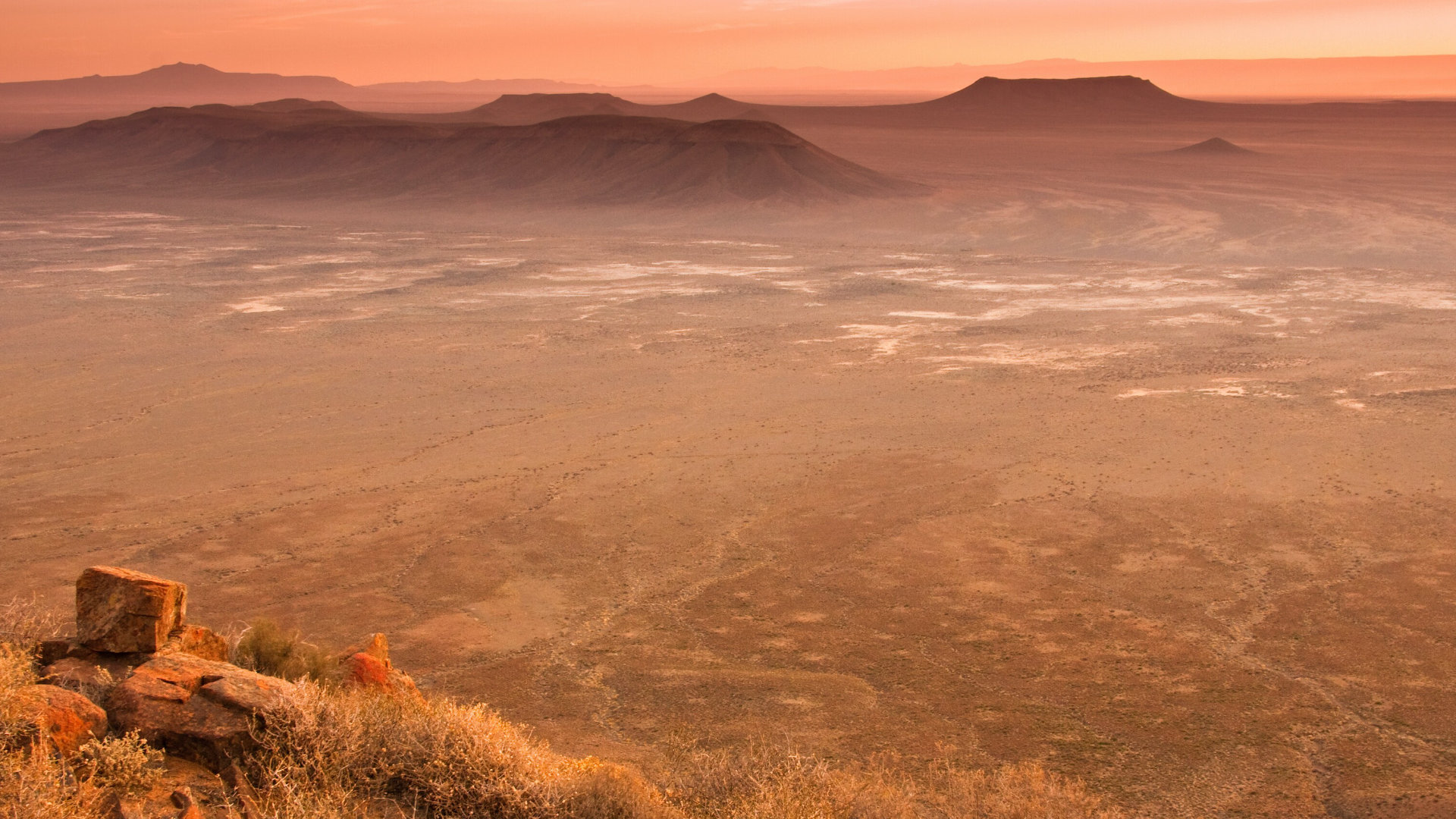 Tankwa plain at dusk — empty horizon, koppies silhouetted, sky going molten.